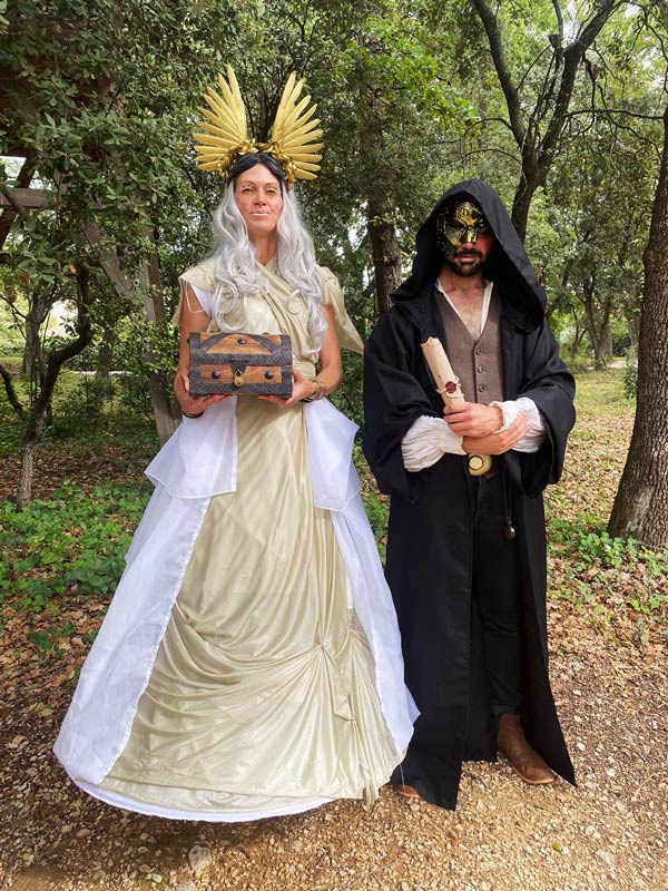 Deux comédiens costumés en personnages de quête, un coffre à la main