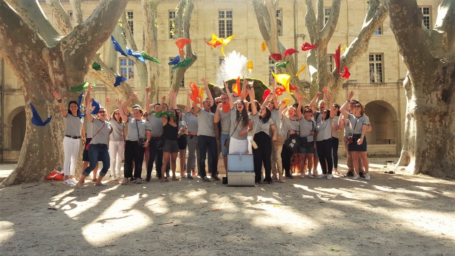 Un grand groupe lance des foulards sur une place ensoleillée