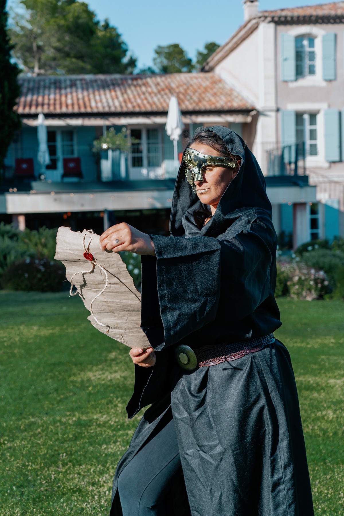 Une comédienne masquée et en cape lit un parchemin