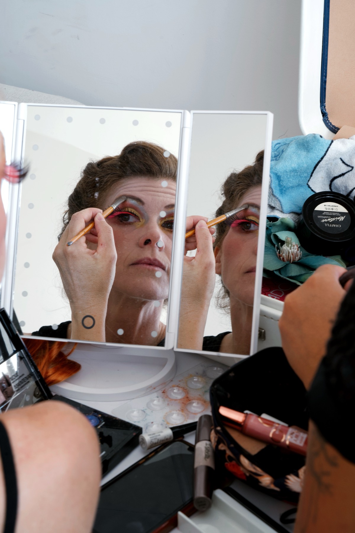 Une comédienne se maquille devant un miroir